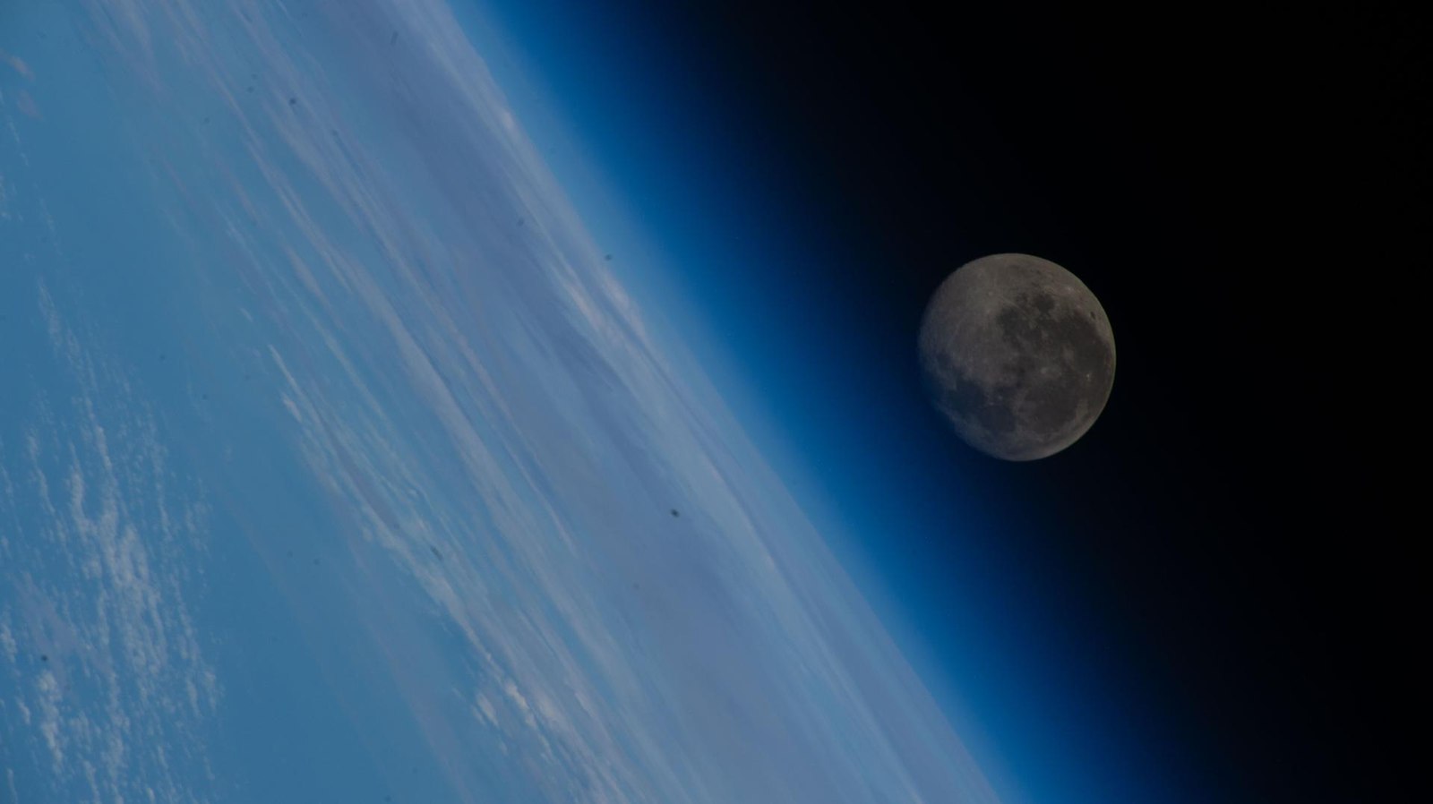 The waning gibbous Moon above Earth's blue atmosphere, photographed from the International Space Station
