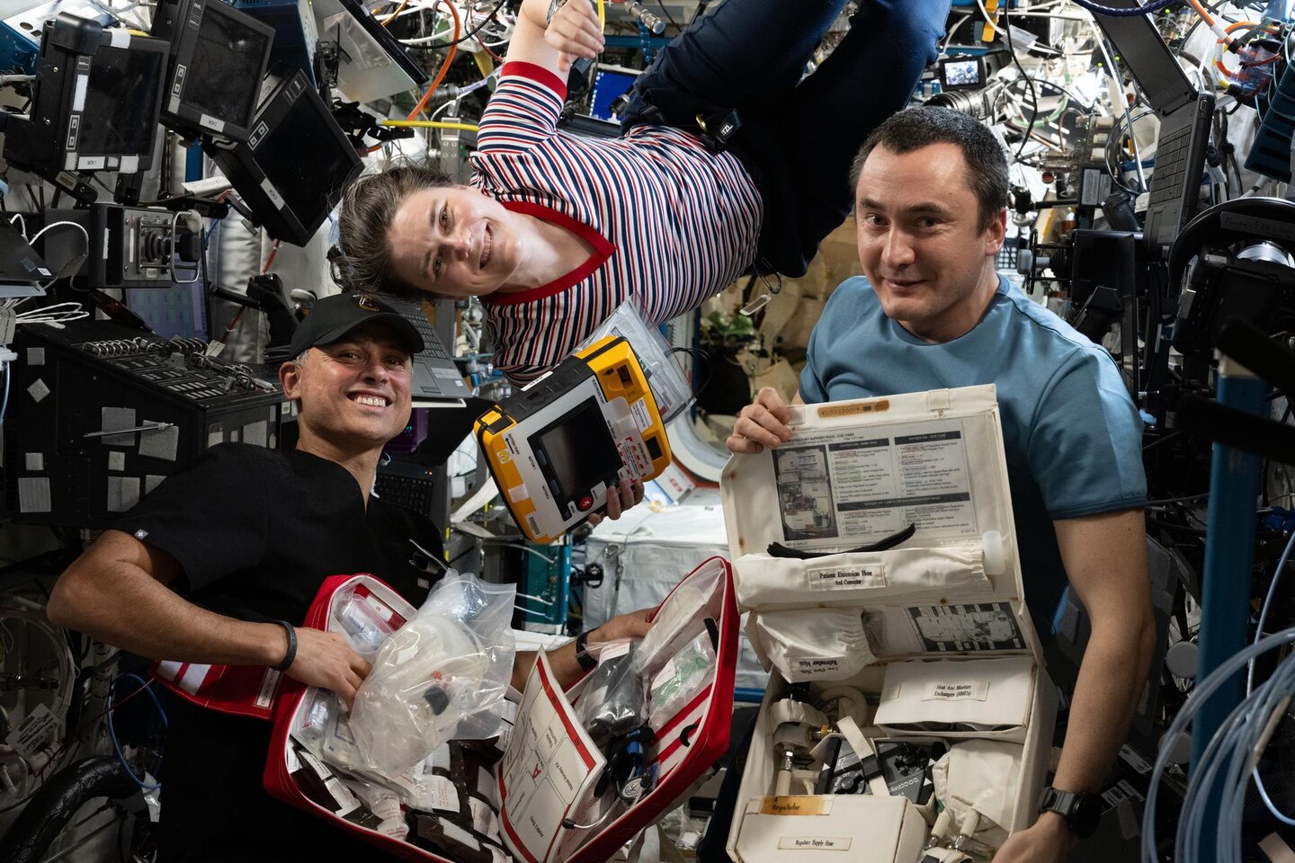 Expedition 75 crew members check emergency medical equipment aboard the International Space Station.