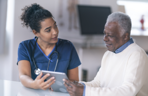 Illustrative photograph of a clinician showing information on a tablet to an older patient